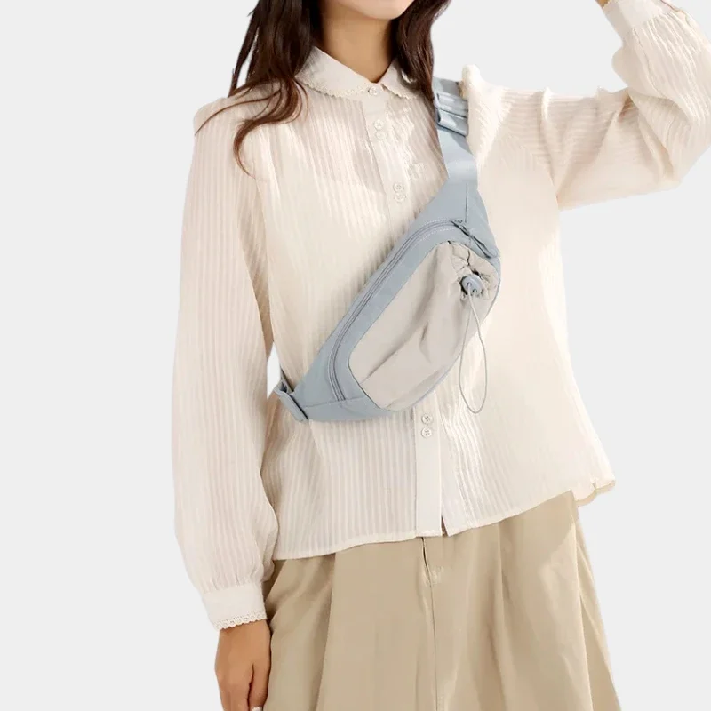 Sac banane en nylon bleu ciel porté en bandoulière sur la poitrine par une femme, de face