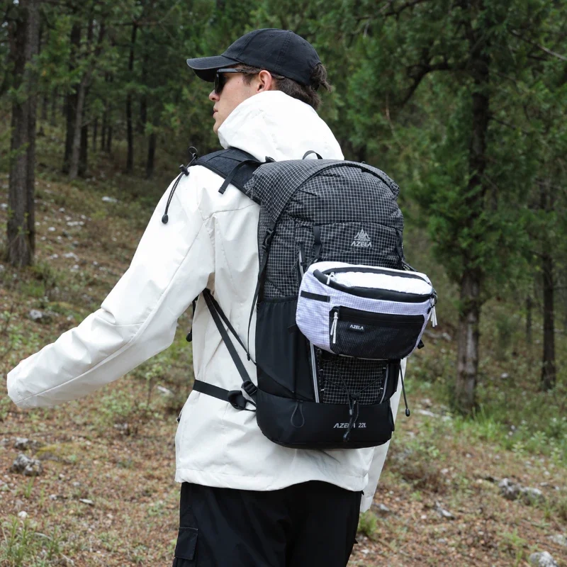 Sac banane ripstop blanc accroché sur un sac à dos porté par un homme en randonnée en forêt