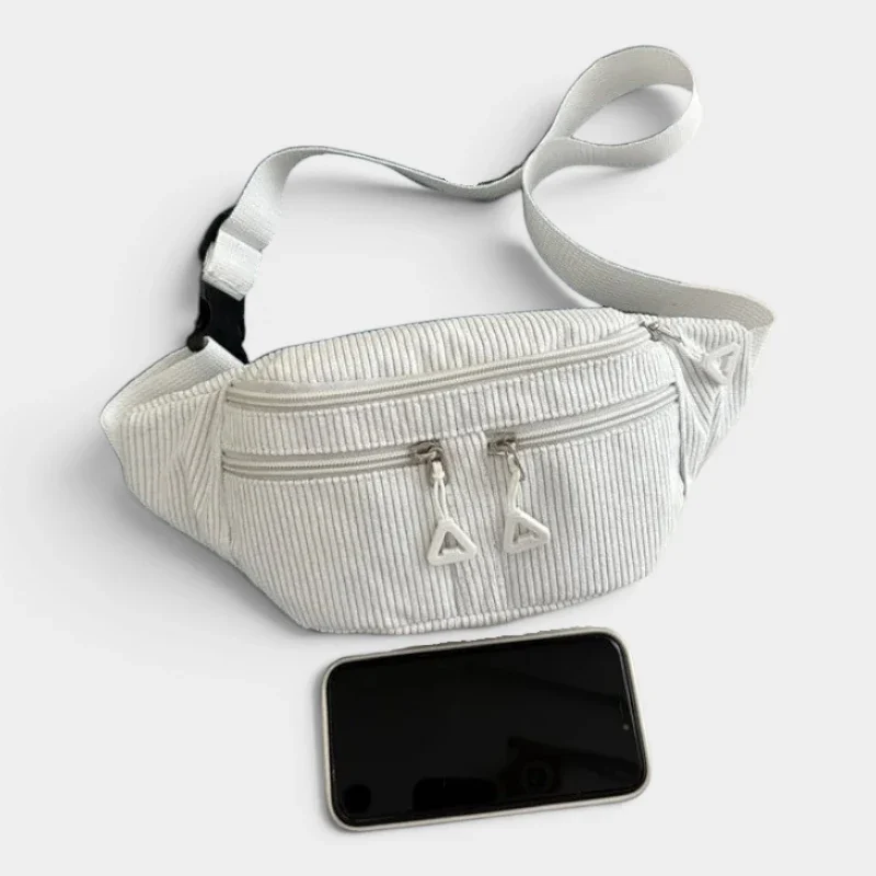 Sac banane velours côtelé blanc posé à plat de face, avec fermeture zippée blanche et un smartphone placé devant