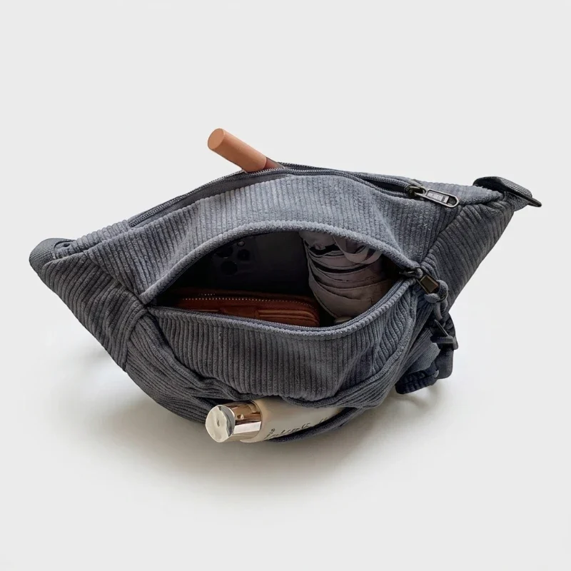 Sac banane velours côtelé gris ardoise vu de dessus face, poche principale ouverte révélant un portefeuille et une bouteille