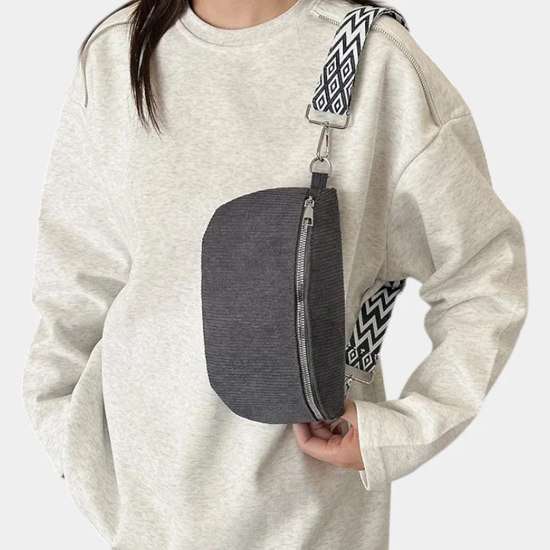 Sac banane velours côtelé gris porté en bandoulière par une femme, avec sangle à motif ethnique