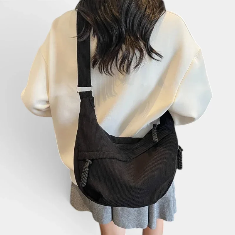 Sac banane velours côtelé noir porté en bandoulière dans le dos par une femme au style casual-chic