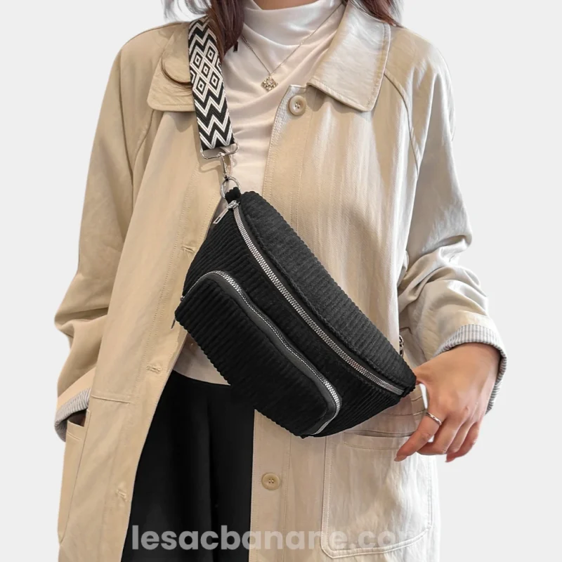 Sac banane velours côtelé noir porté en bandoulière par une femme avec sangle jacquard à motif géométrique