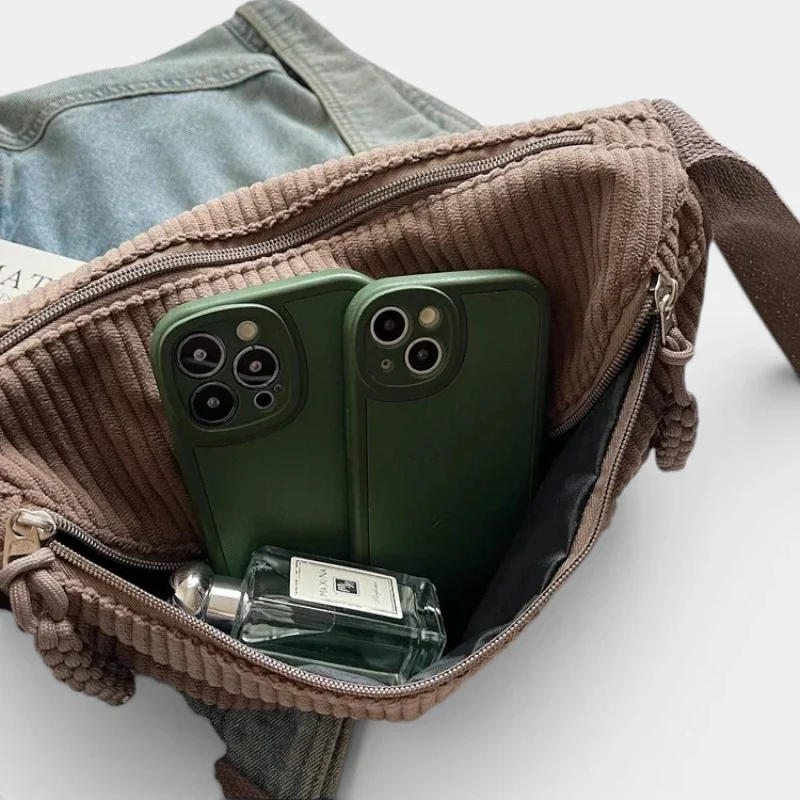 Sac banane en velours côtelé taupe, poche principale ouverte révélant deux smartphones et un parfum Jo Malone