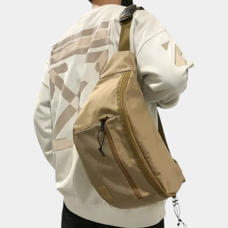 Grand sac banane XXL en nylon beige porté en bandoulière dans le dos par un homme au style streetwear